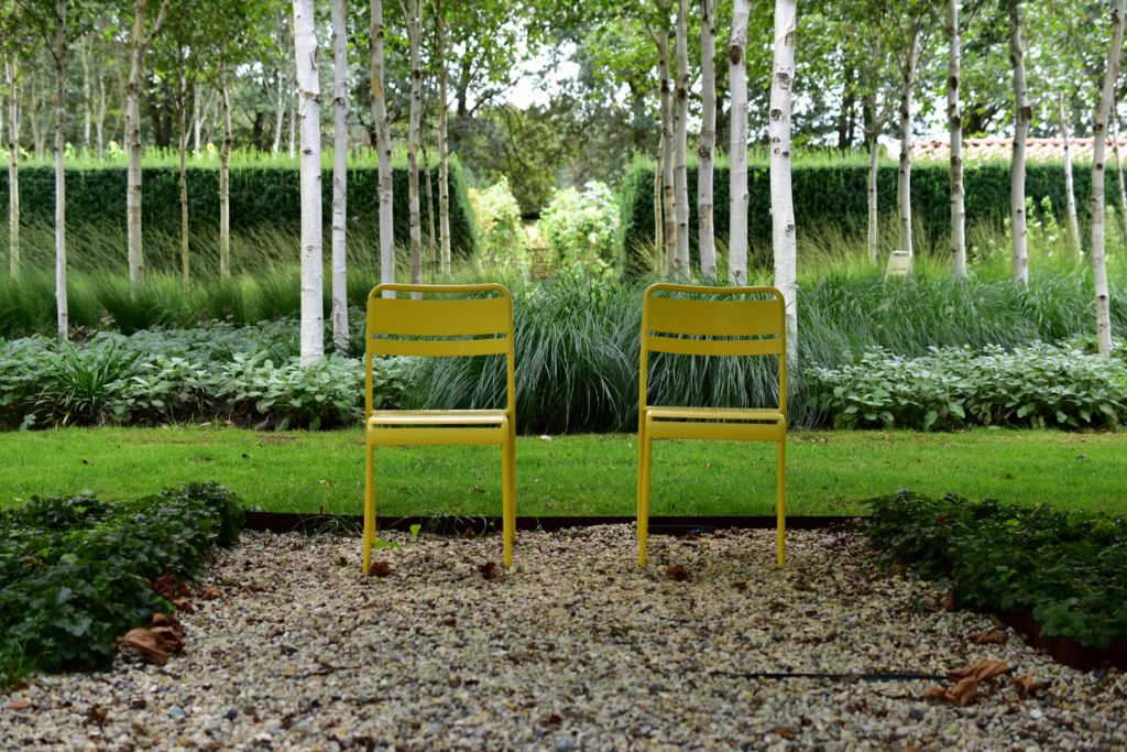 2 chaises d'extérieur fermob jaunes dans un jardin à la française